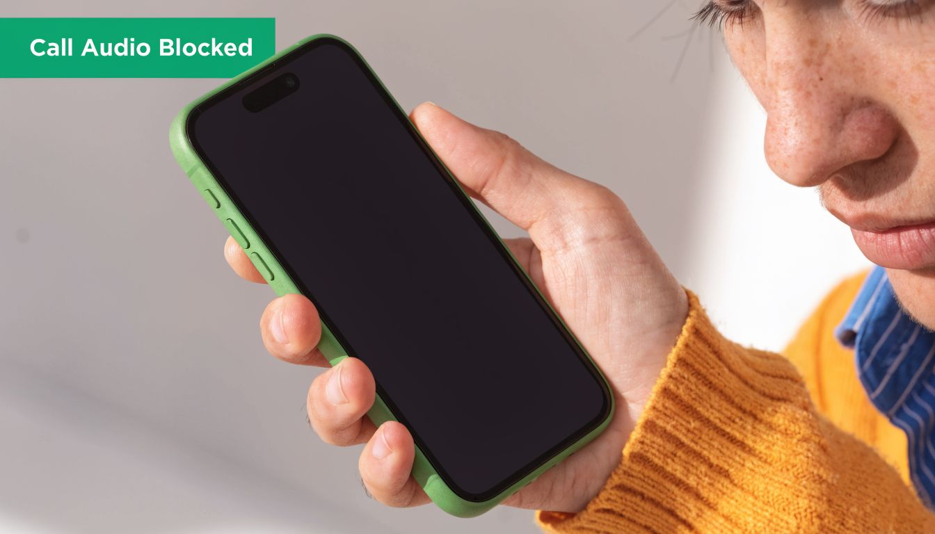 A close-up of a person holding a smartphone showing a Call Audio Blocked alert message.