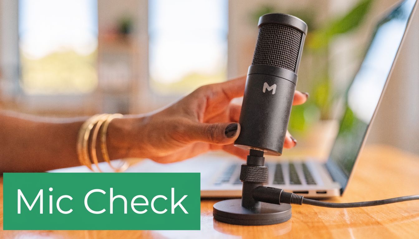 A close-up of a person's hand adjusting a black microphone connected to a laptop for recording.